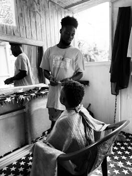 Intimate black and white photo of a barbershop interaction, capturing authenticity.