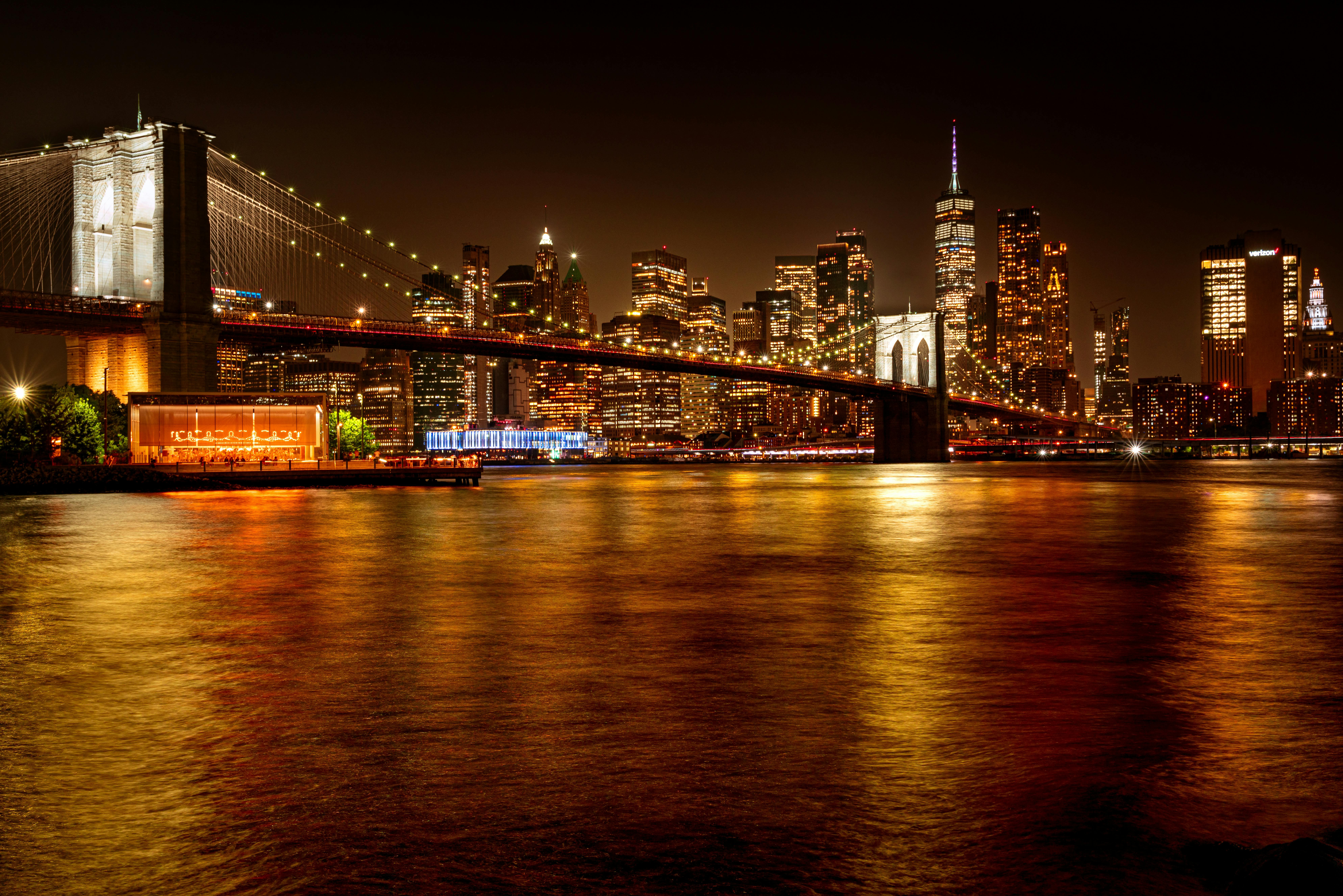 Captivating night view of the illuminated Brooklyn Bridge and Manhattan skyline reflecting on the East River
