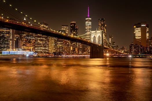 Captivating nighttime shot of the Brooklyn Bridge and Manhattan skyline under a golden glow.