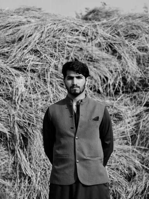 Free Portrait of a handsome man wearing traditional shalwar kameez against a rustic hay background. Stock Photo