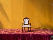 An ornate armchair on a colorful stage backdrop in Mangaluru, India.