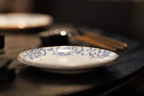 Free Close-up of a blue and white ceramic plate with wooden cutlery on a rustic table, creating a cozy dining ambiance. Stock Photo