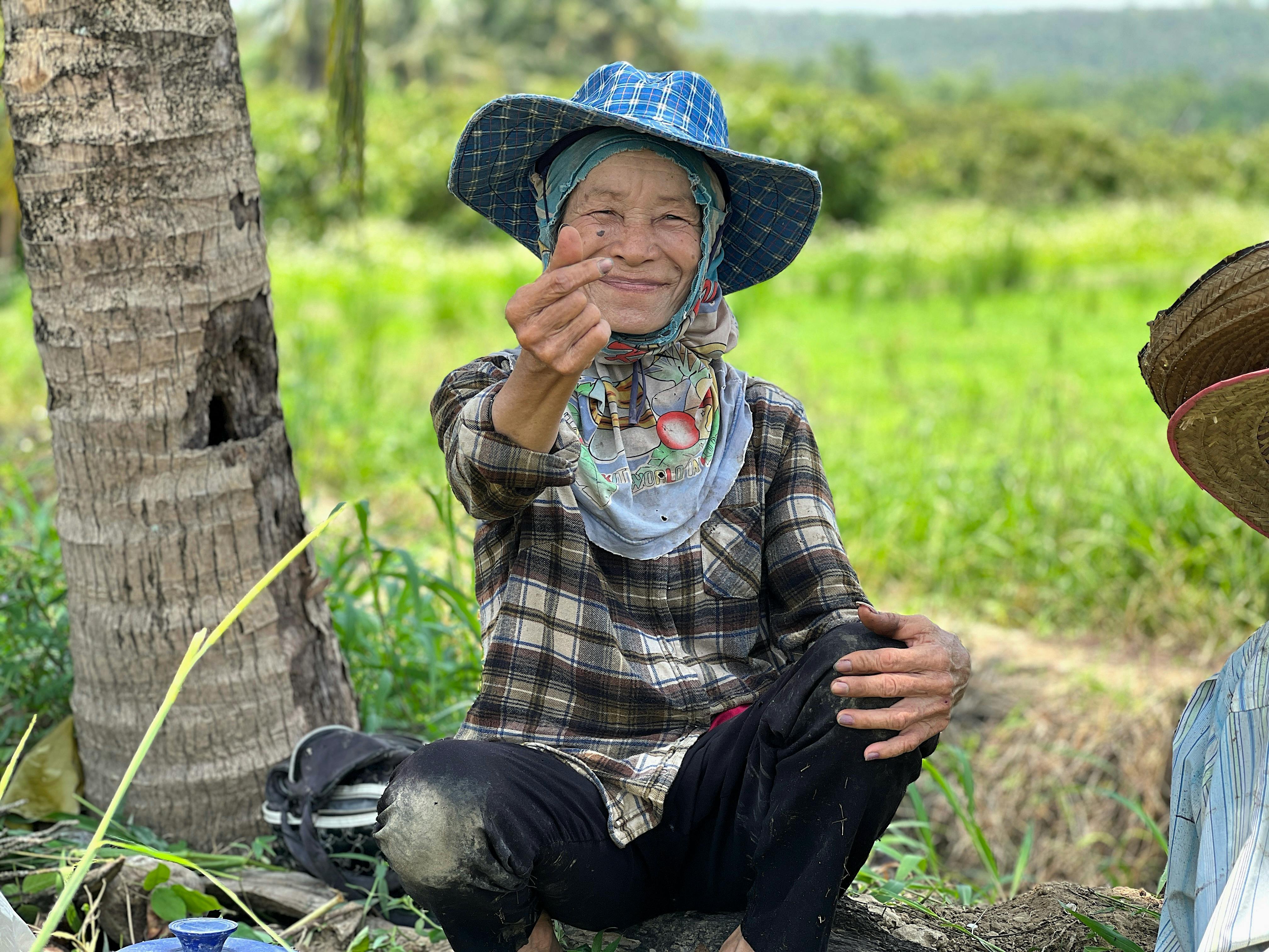 Candid portrait of an elderly Thai farmer in traditional attire relaxing in the fields of Chiang Mai.