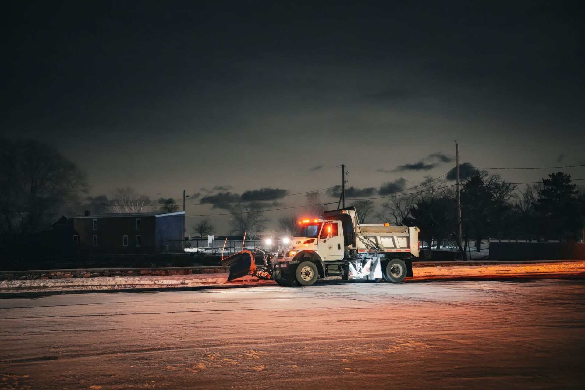 Snow plow clearing a road at night with glowing lights