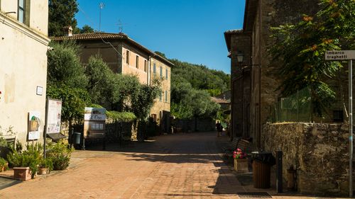 Free Scenic small town street in Umbria, Italy with rustic architecture and lush greenery under a bright blue sky. Stock Photo