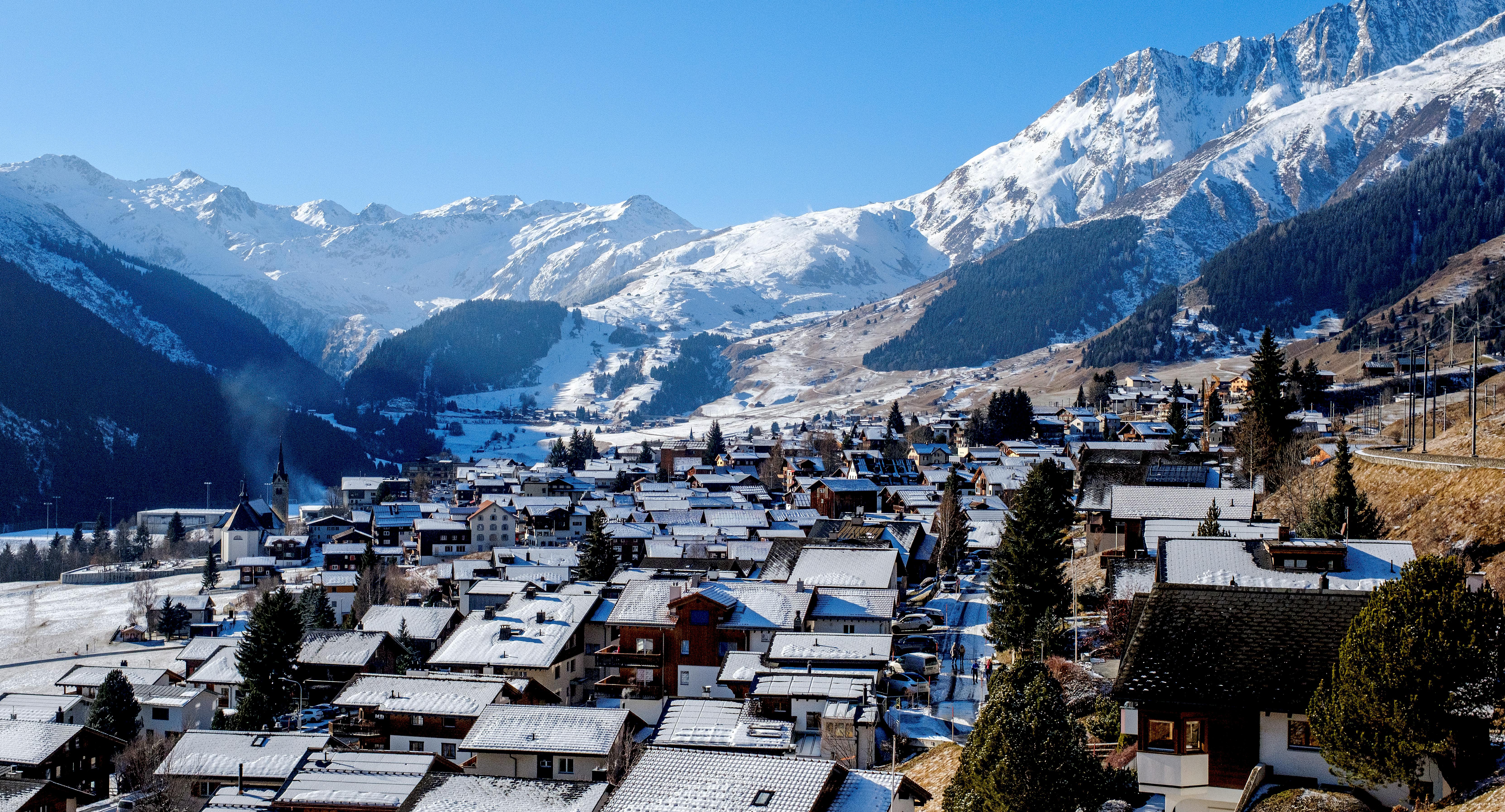 Beautiful winter view of a Swiss village nestled in the Alps with snow-covered rooftops.