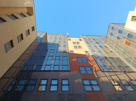 Upward view of modern architecture featuring glass and concrete facades under a clear blue sky.