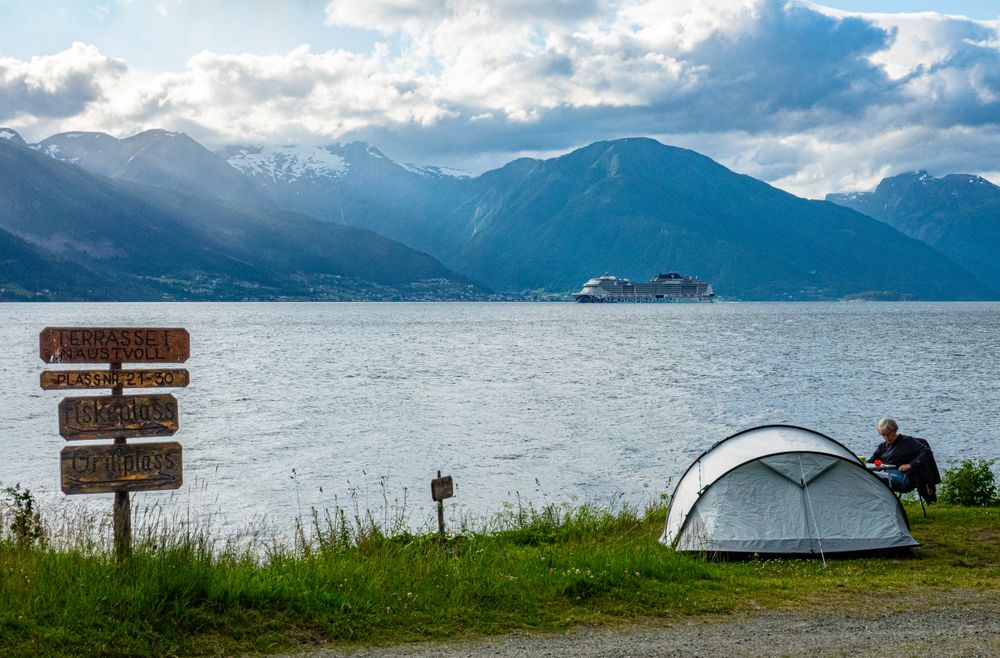 Cort ridicat pe malul unui fiord norvegian, cu munți în fundal
