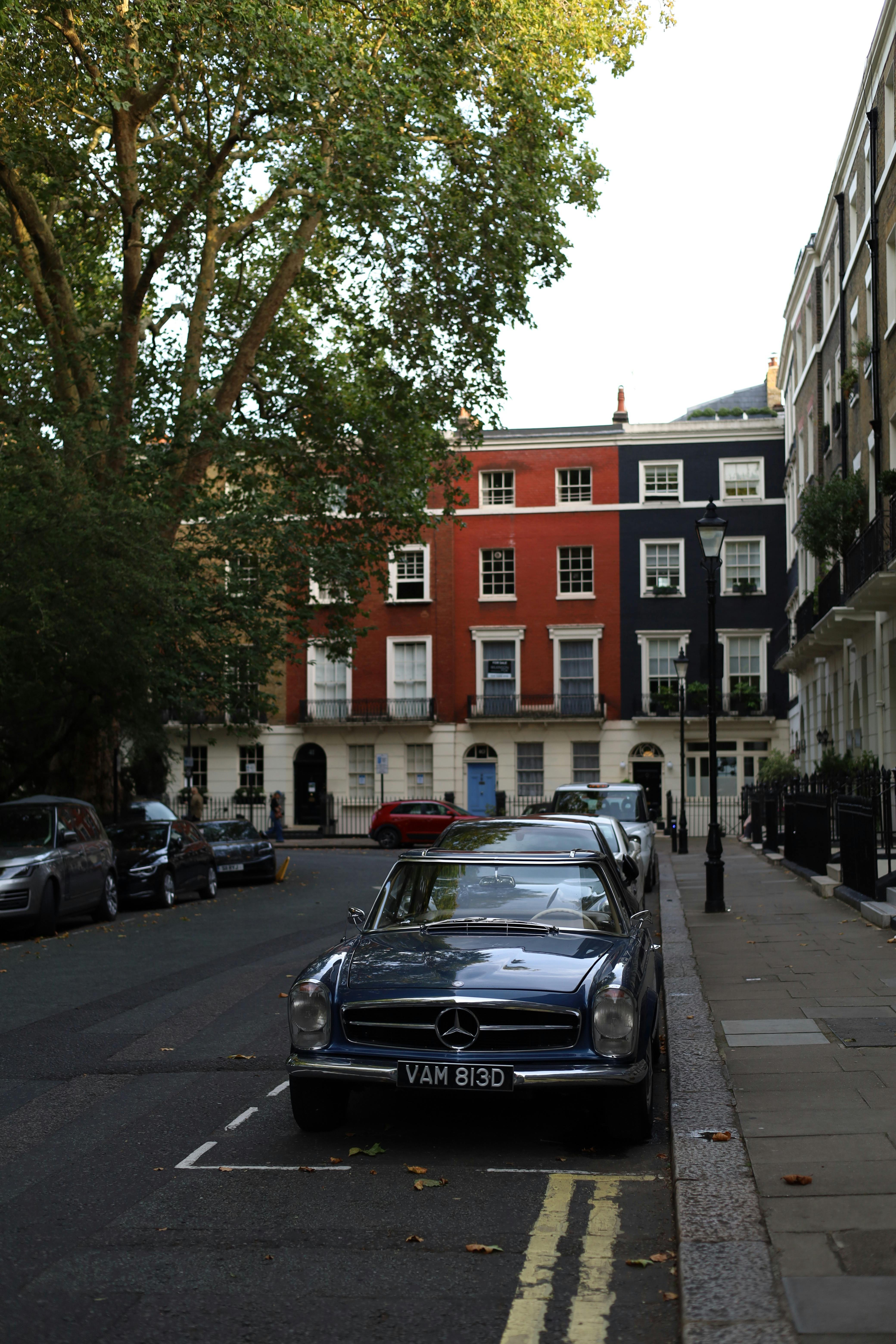 Vintage car parked on a charming European city street with elegant row houses.