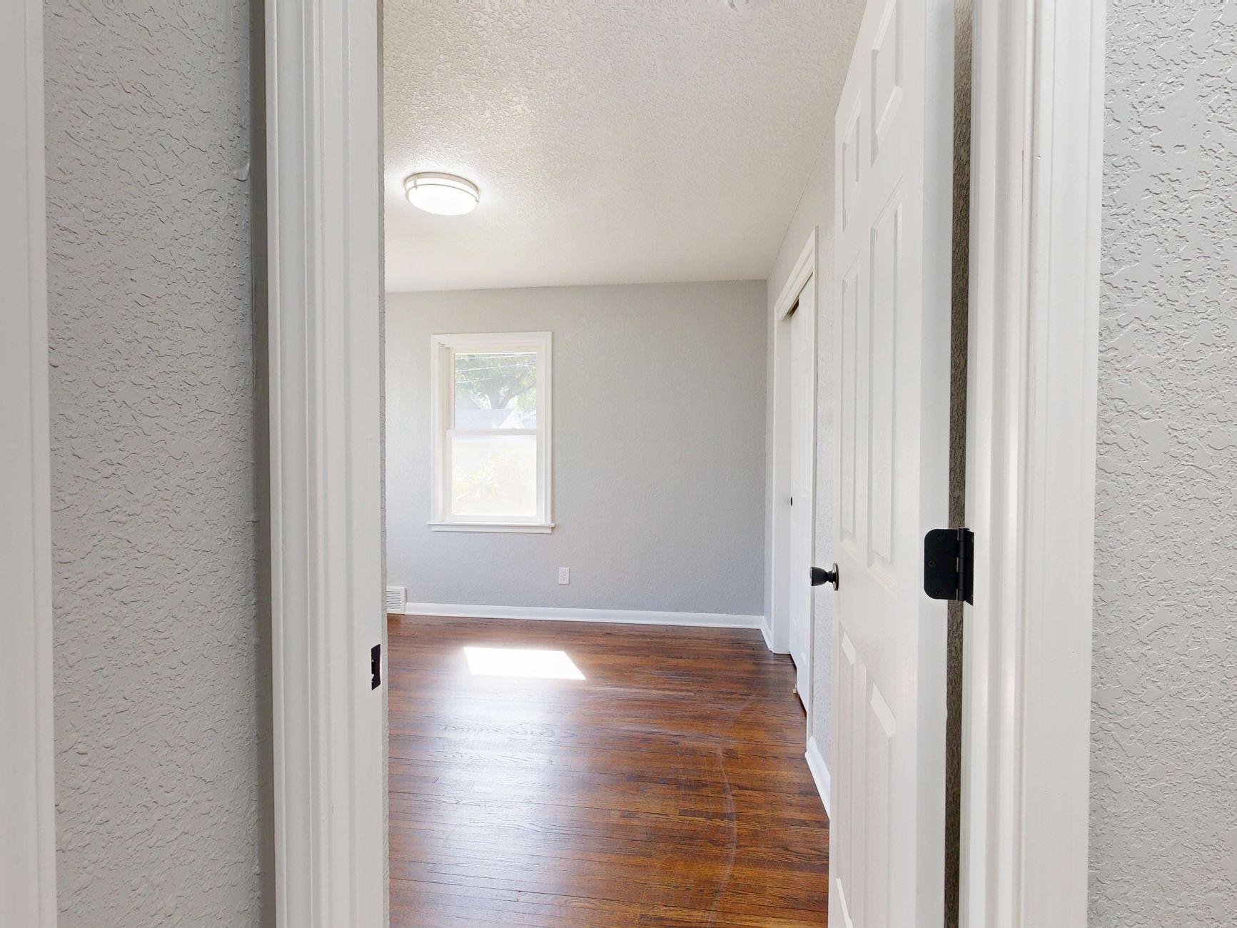 Interior view of an empty room with wooden floors and natural light.