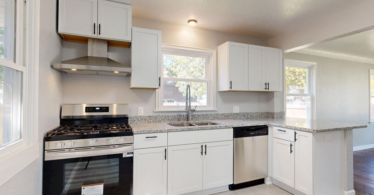 Bright modern kitchen featuring white cabinets and stainless steel appliances.