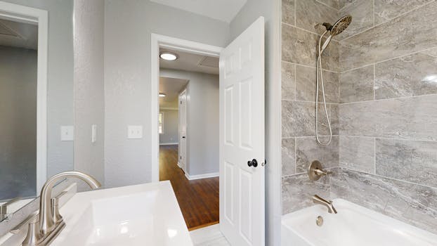 Stylish bathroom with grey tiles, open door, and modern fixtures.