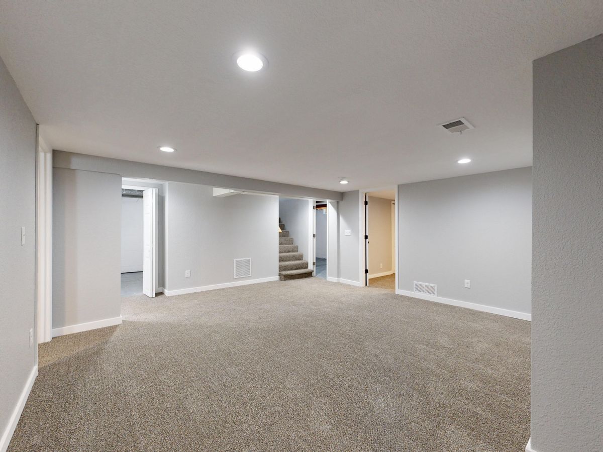 Spacious modern basement with neutral design and carpet flooring, perfect for renovation or real estate listings. Stock Photo.