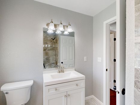 A modern bathroom featuring a sleek vanity, mirror, and elegant light fixtures.