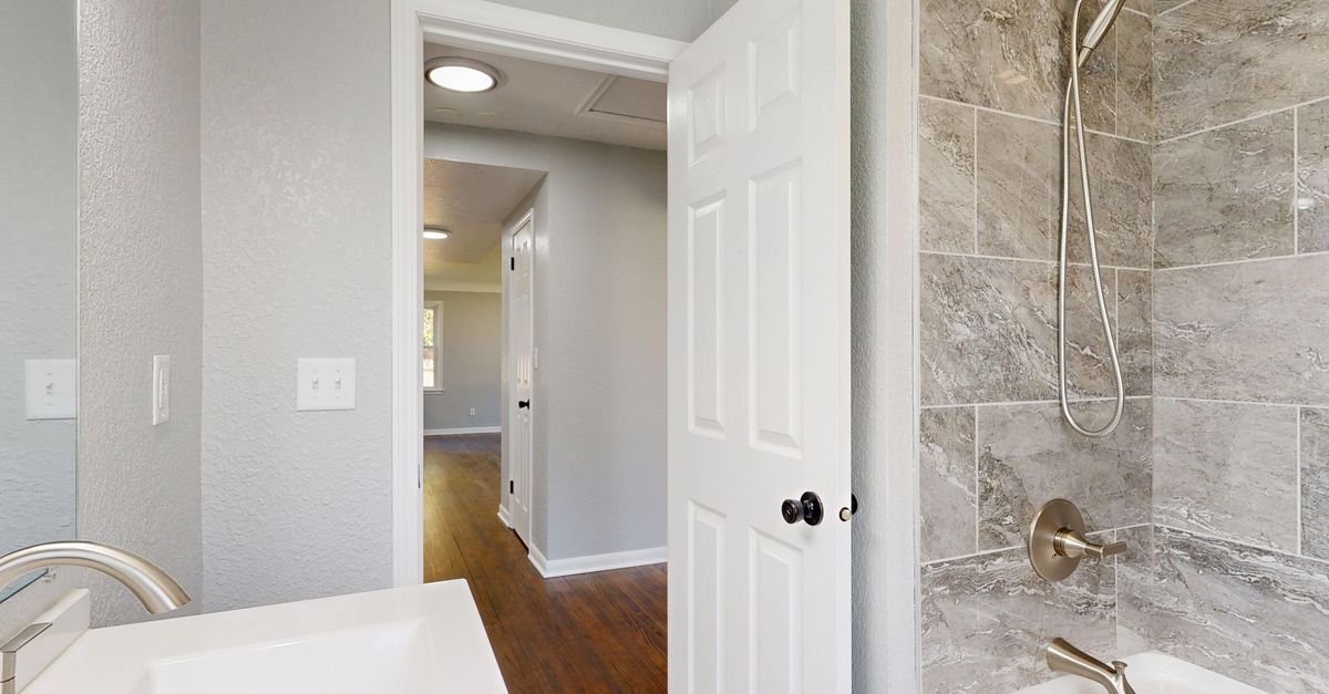 Contemporary bathroom featuring a grey tile shower and sleek fixtures.