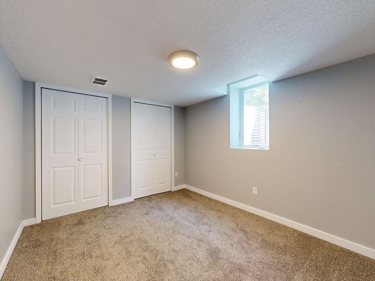 Minimalistic empty room with carpet, two white doors, and natural light from a window. Stock Photo.