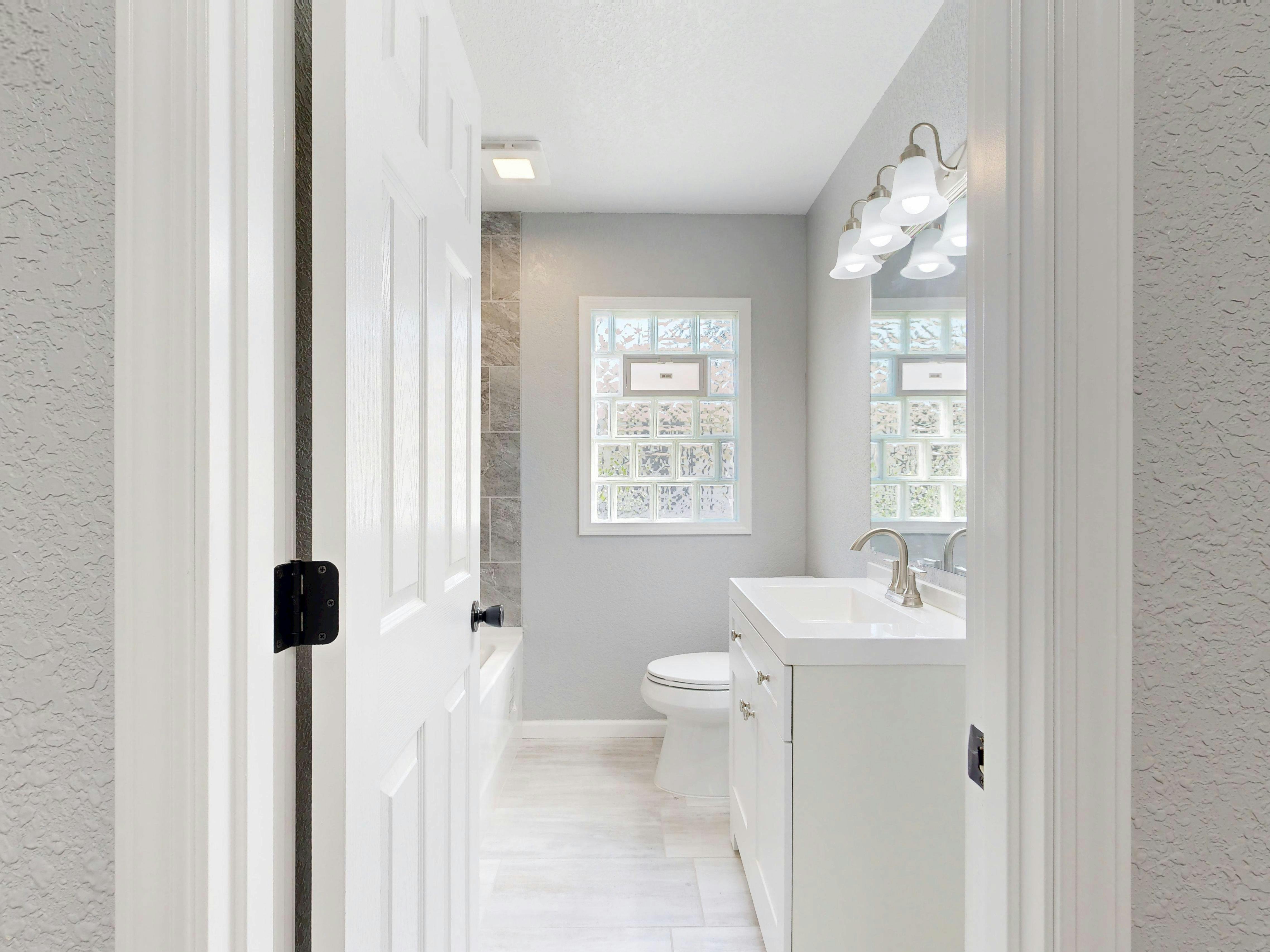 Mała łazienka z białą ścianką z luksferów oddzielającą prysznic