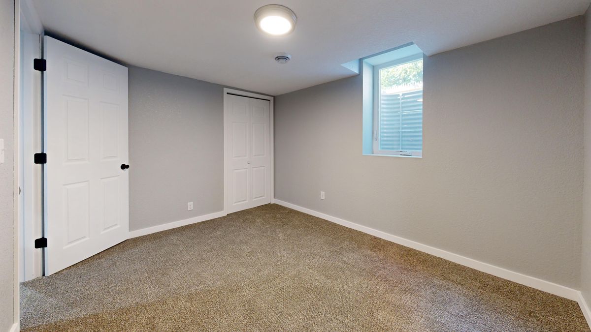Empty room with carpet flooring, white doors, and a window. Ideal for real estate listings. Stock Photo.
