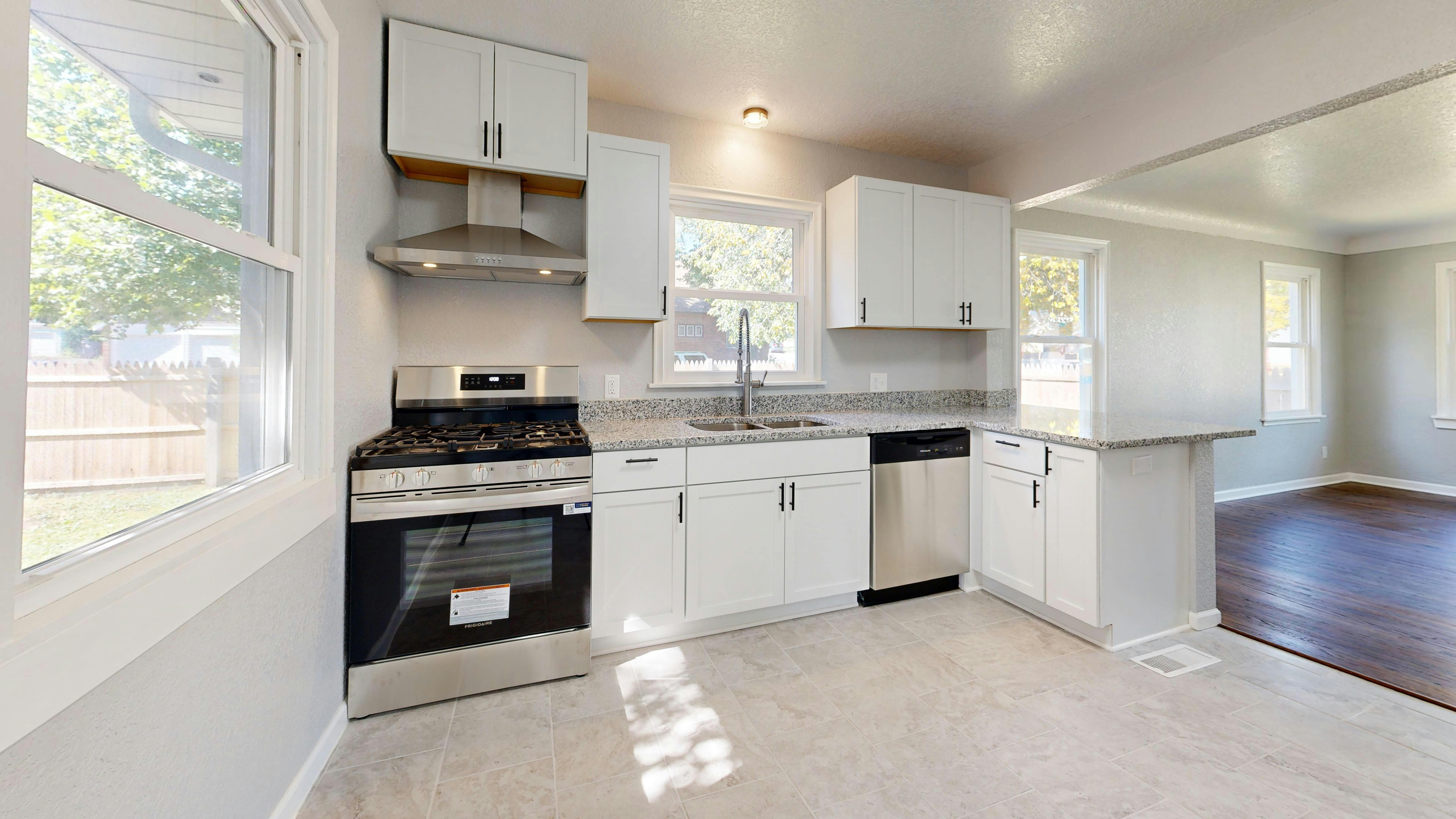 Bright white kitchen with stainless steel appliances, showing typical hiding spots under a countertop and behind a cabinet
