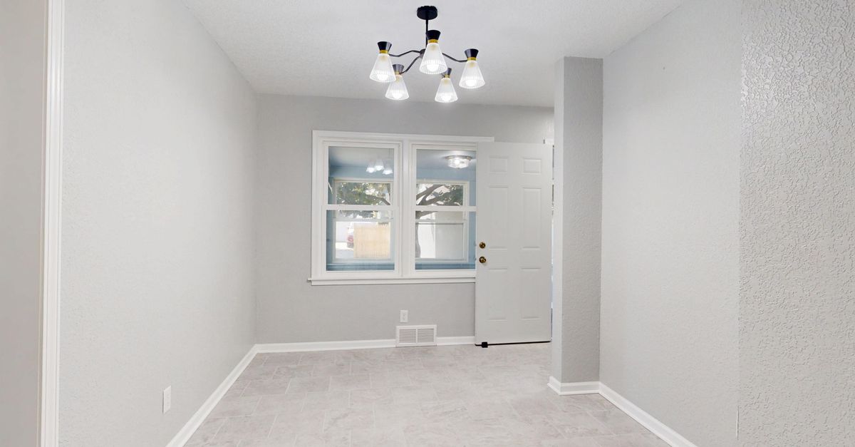 A spacious, empty room with a modern light fixture and large windows showcasing a minimalist design.