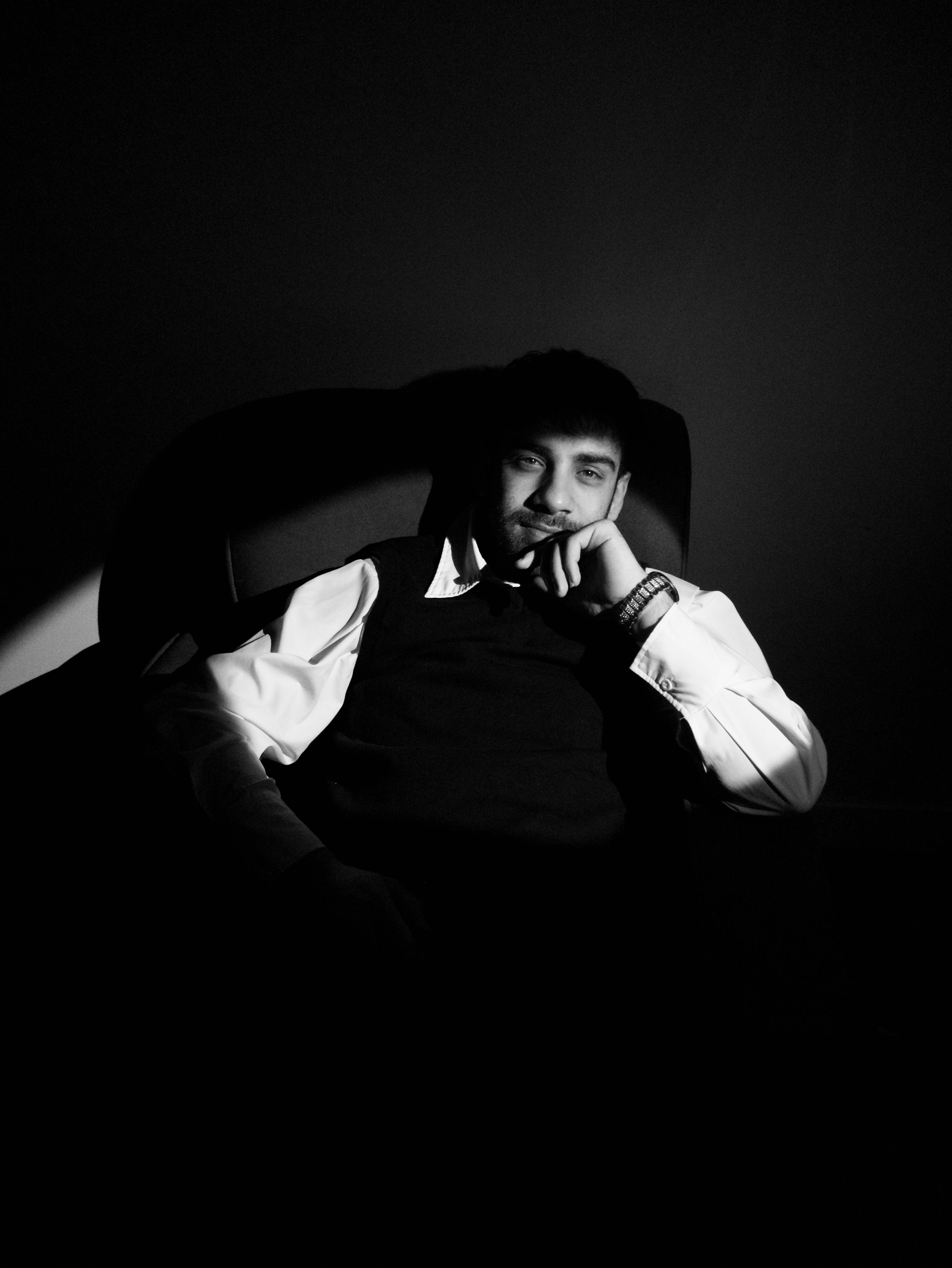 Gratuit Portret alb-negru, sumbru, al unui bărbat așezat gânditor în umbră. Fotografie de stoc