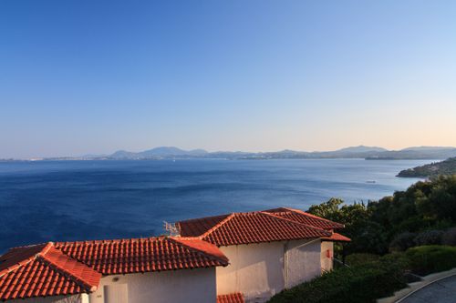 Free Breathtaking view of Korfu coastline with traditional red-roofed houses and the Ionian Sea at sunset. Stock Photo