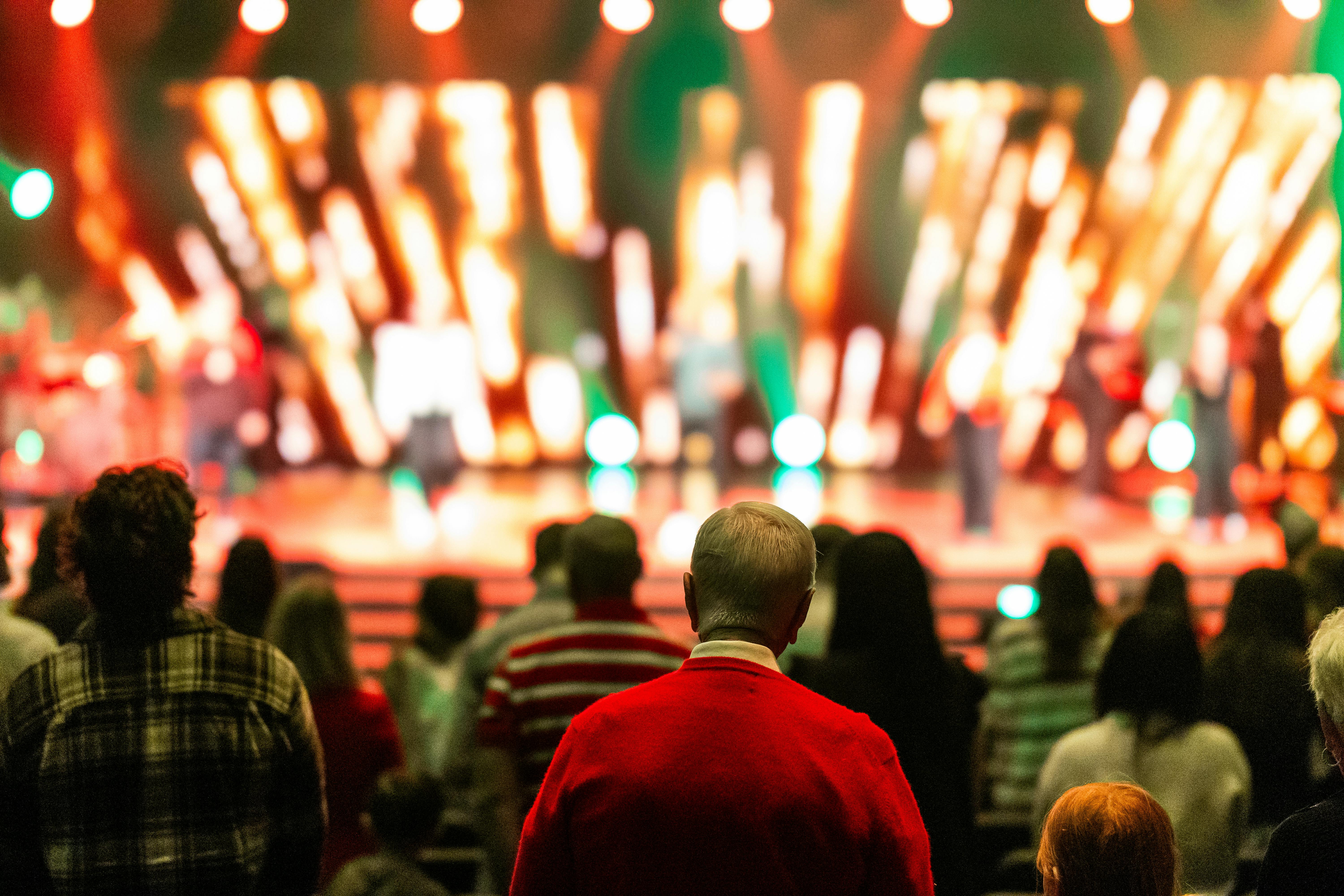 Free A diverse crowd watches a colorful stage performance in a lively concert atmosphere. Stock Photo