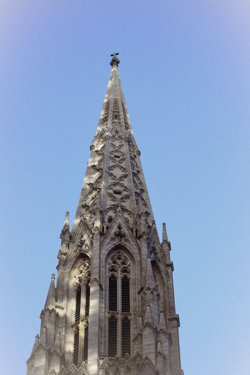 Free Close-up of a Gothic church spire reaching into a clear blue sky in New York City. Stock Photo