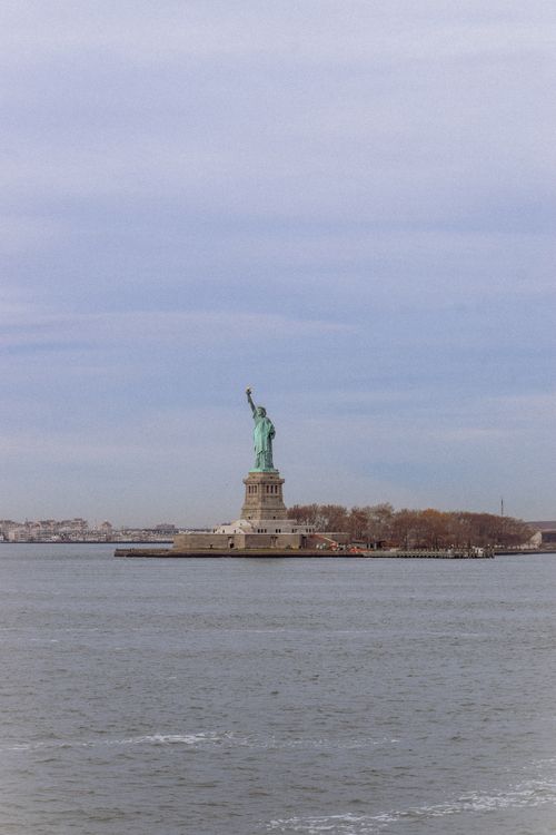 Free Majestic view of the Statue of Liberty standing in New York Harbor against a tranquil blue sky. Stock Photo