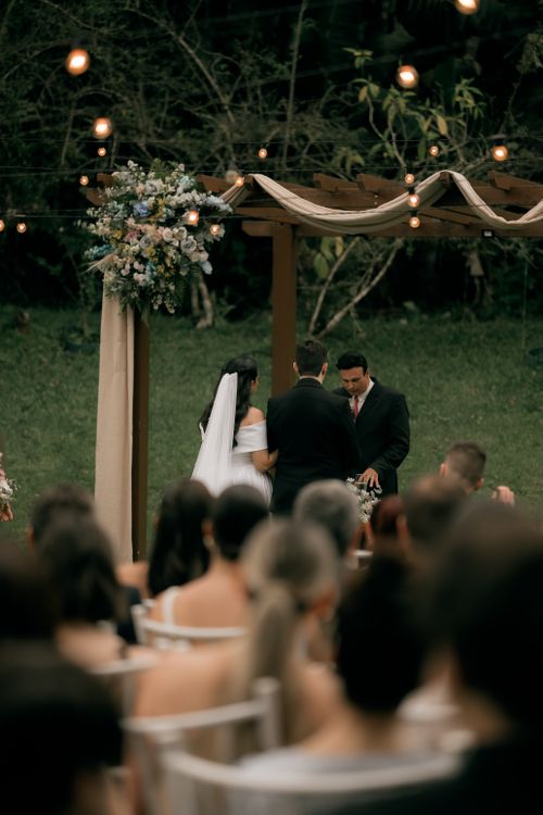 Free Elegant outdoor wedding ceremony under floral arch, capturing romance and celebration. Stock Photo