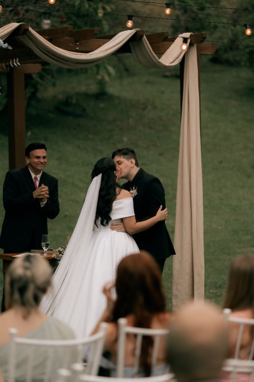 Free Couple shares first kiss at outdoor wedding under elegant arch. Stock Photo