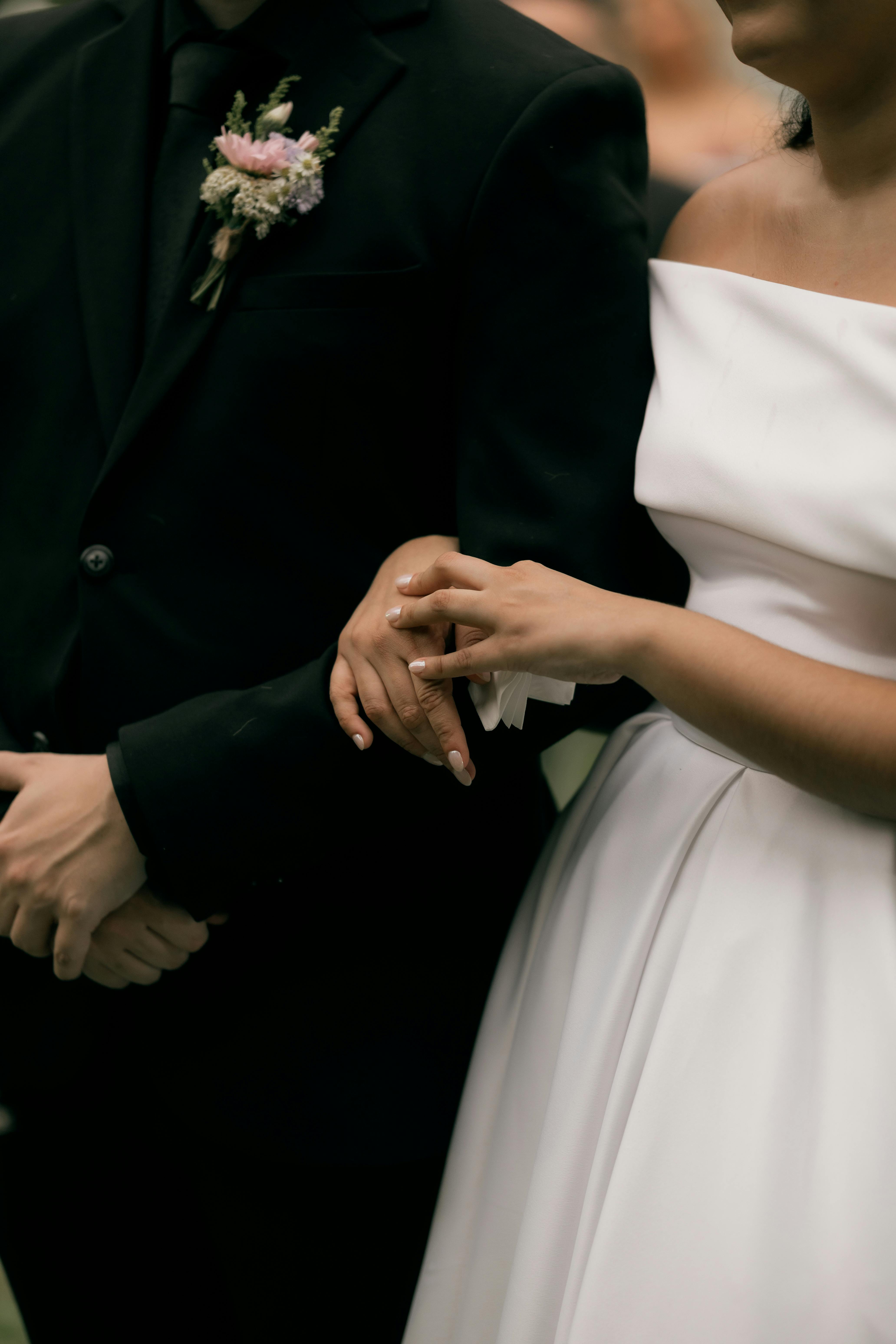 Gratis Un momento íntimo entre los novios tomados de la mano durante su elegante ceremonia de boda. Foto de stock