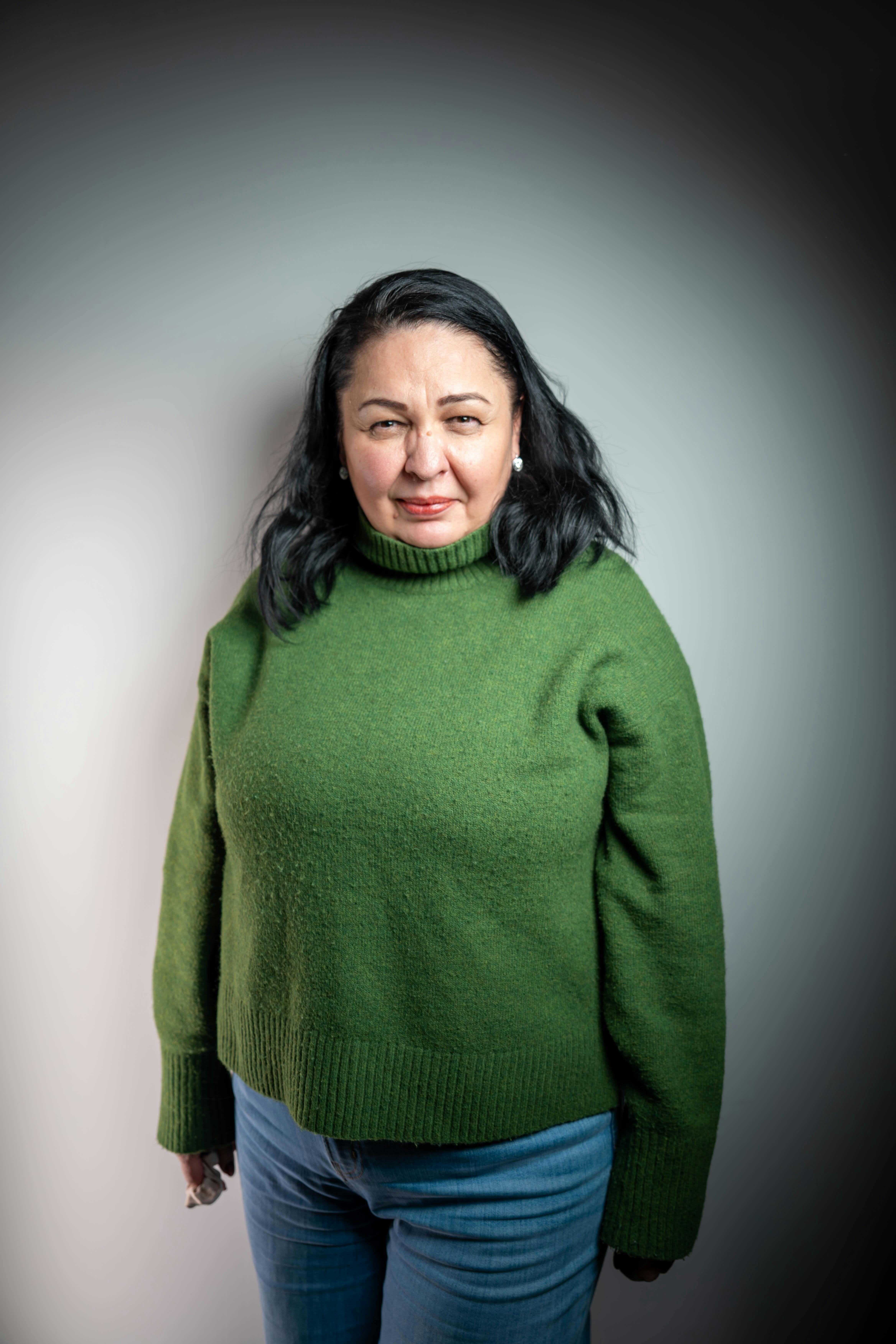 Gratis Retrato en primer plano de una mujer con un suéter verde sobre un fondo liso y suavemente iluminado. Foto de stock