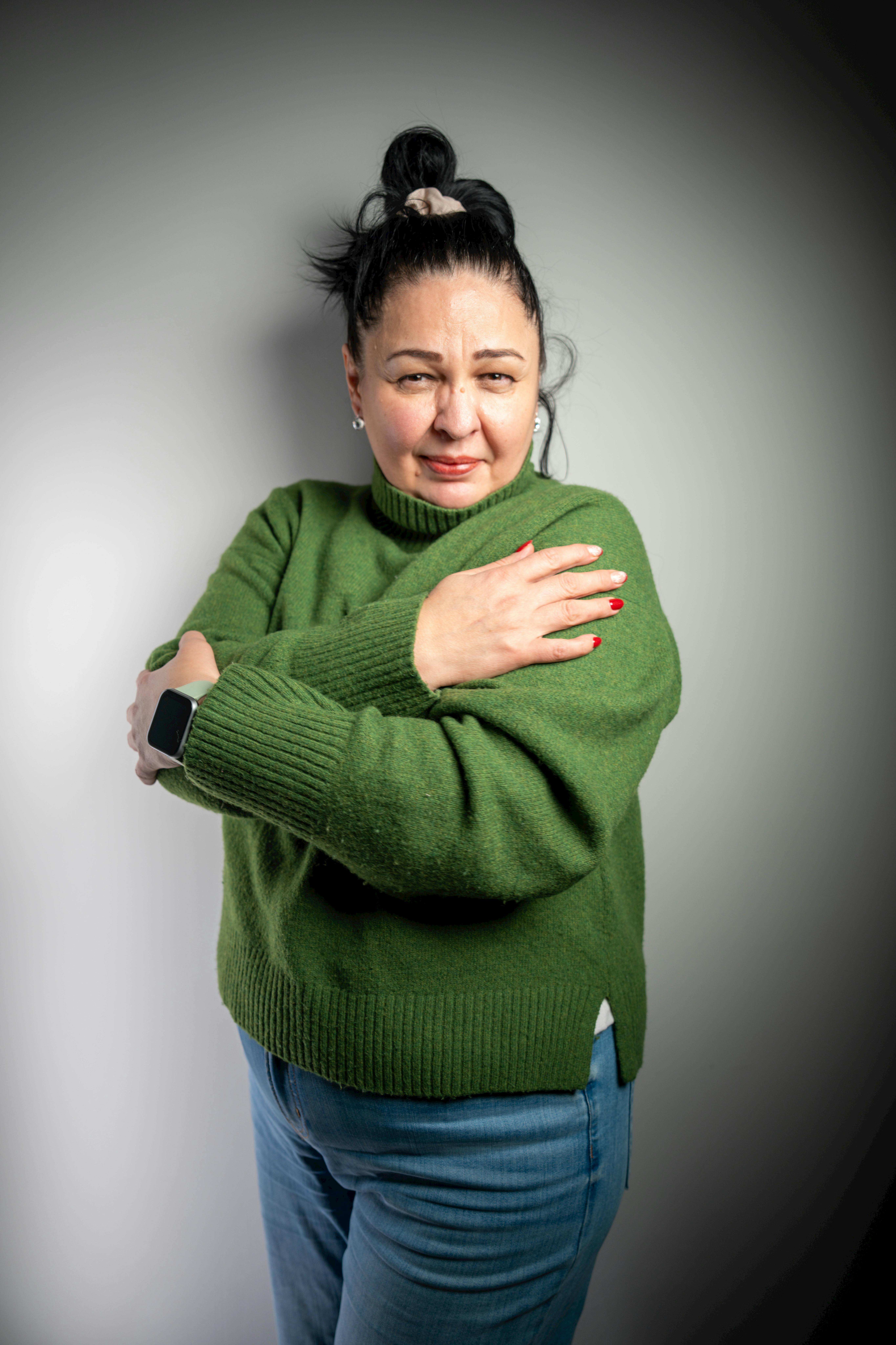 Gratis Mujer adulta que viste un suéter verde y un reloj inteligente, expresando confianza en el interior. Foto de stock