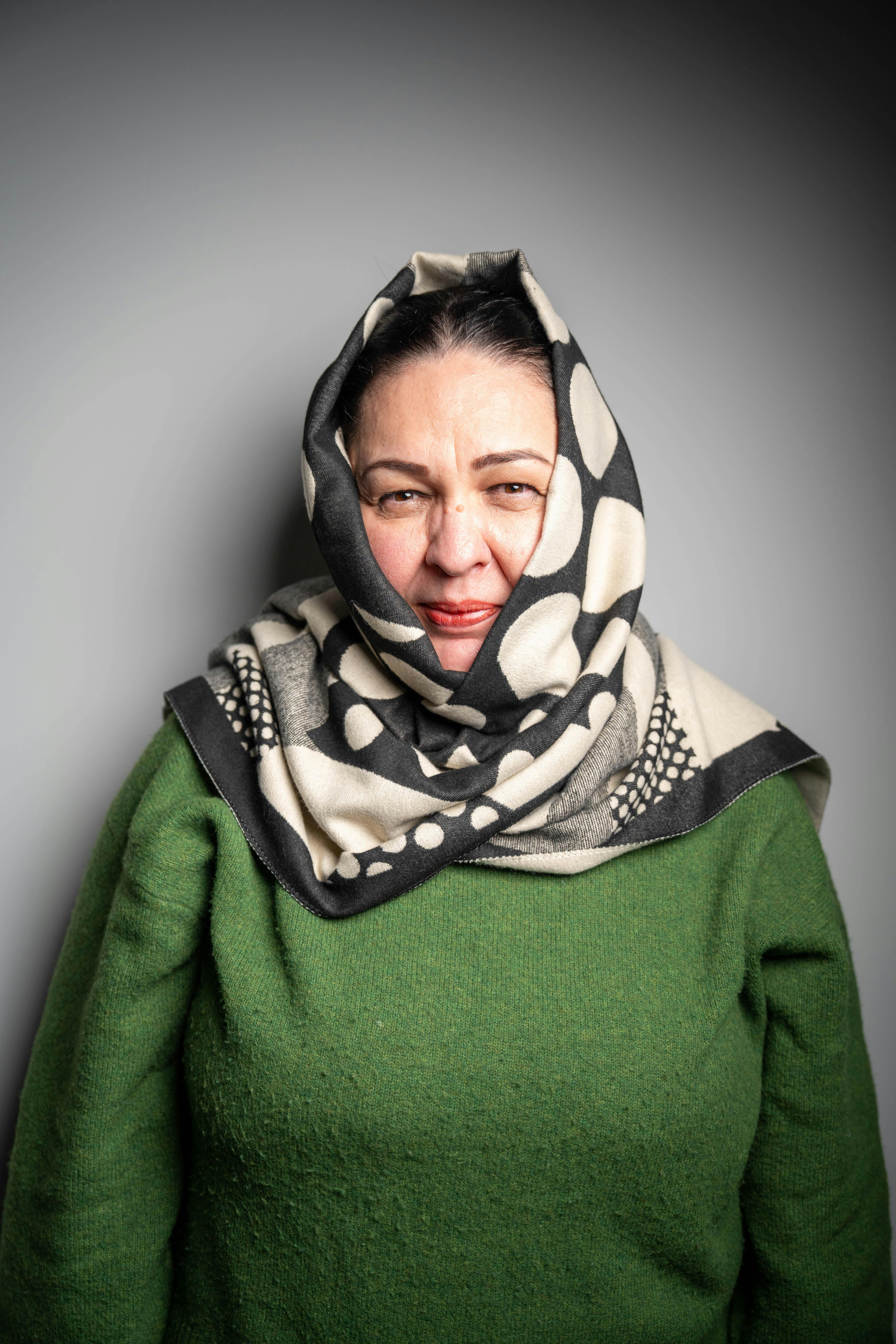 Gratis Mujer que lleva un suéter verde y una bufanda estampada sobre un fondo neutro. Foto de stock