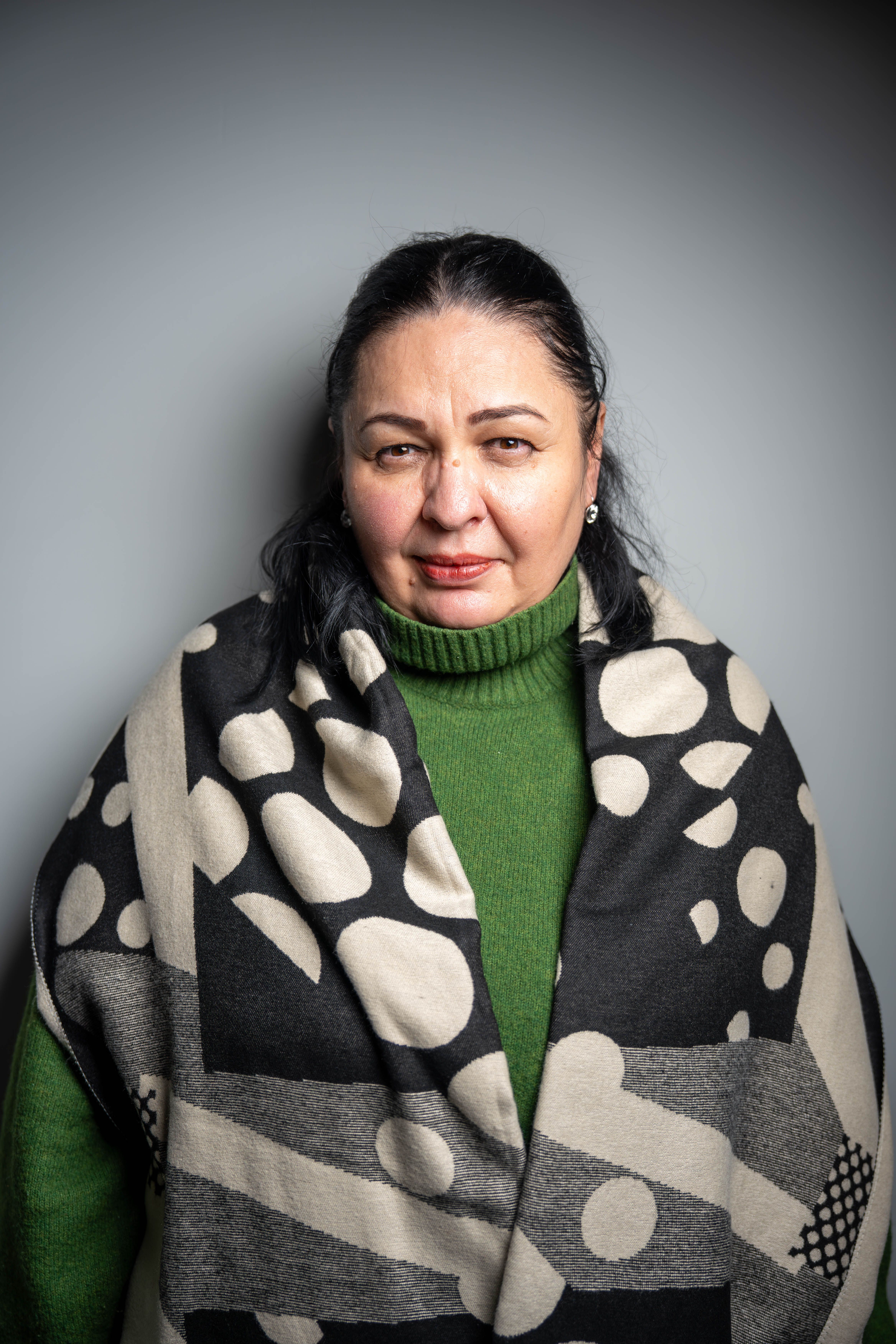 Elegant portrait of a middle-aged woman in a green sweater and artistic scarf.