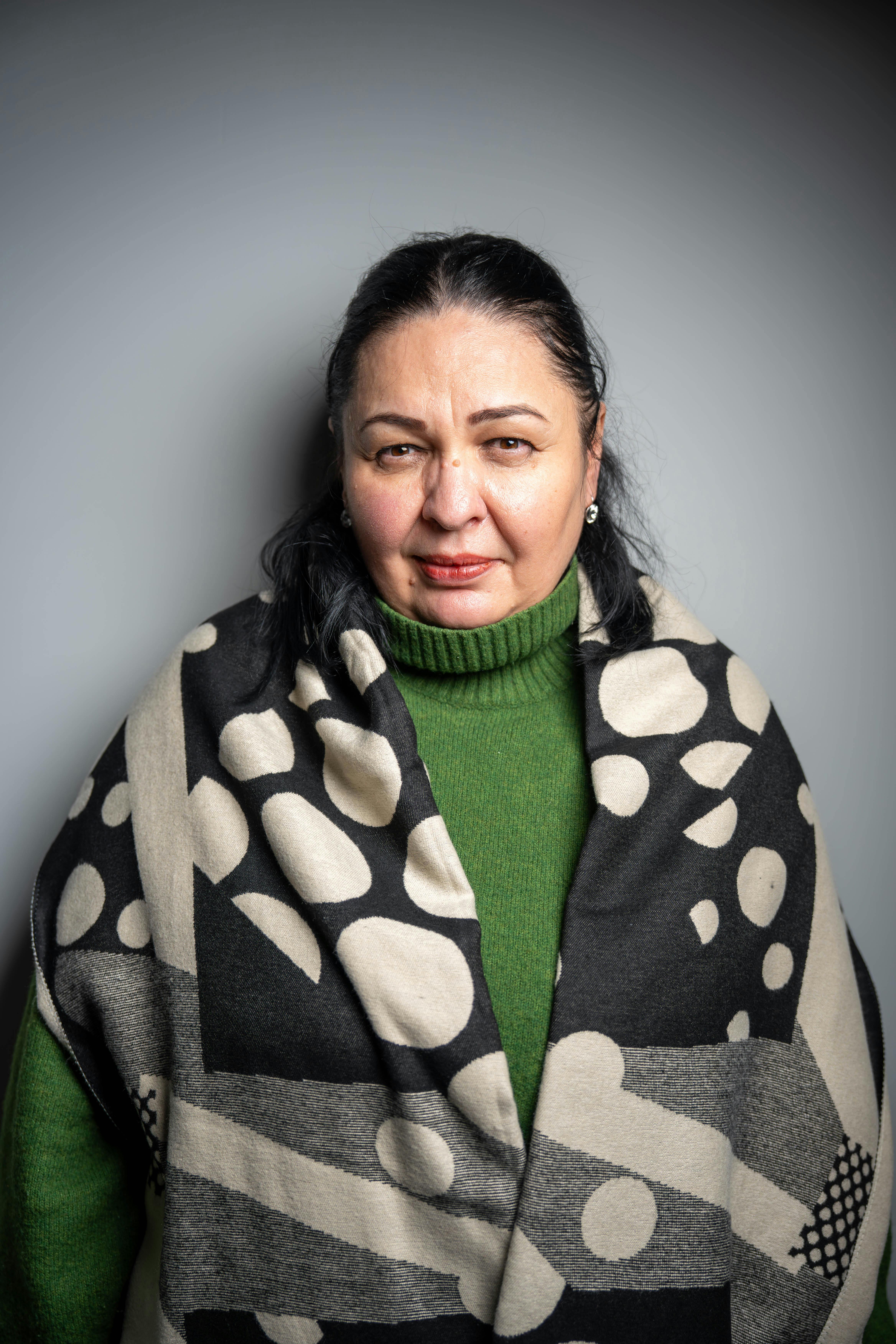 Gratis Elegante retrato de una mujer de mediana edad con un suéter verde y una bufanda artística. Foto de stock