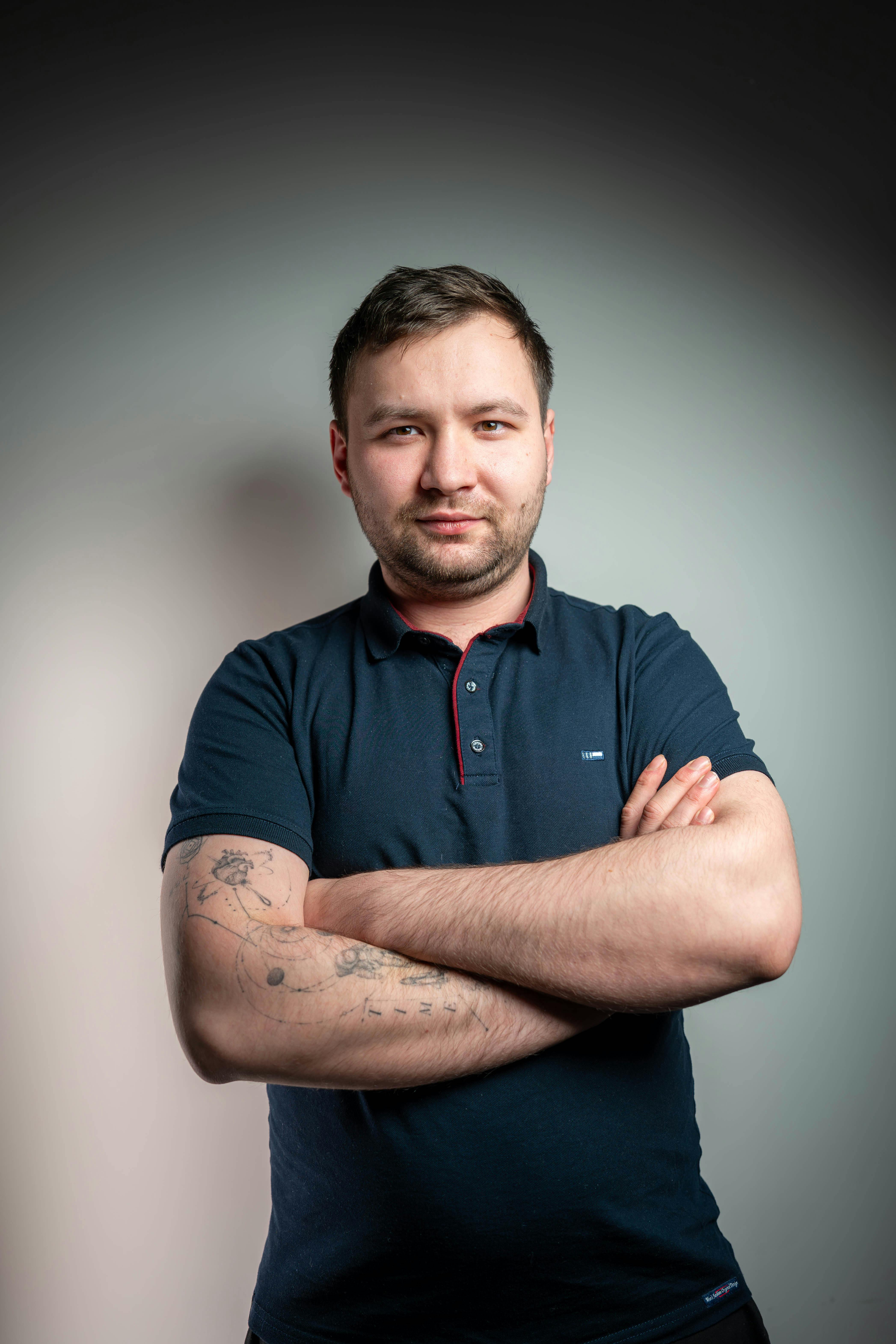 grátis Retrato de um homem confiante com os braços cruzados, exibindo suas tatuagens, em um estúdio profissional. Foto profissional