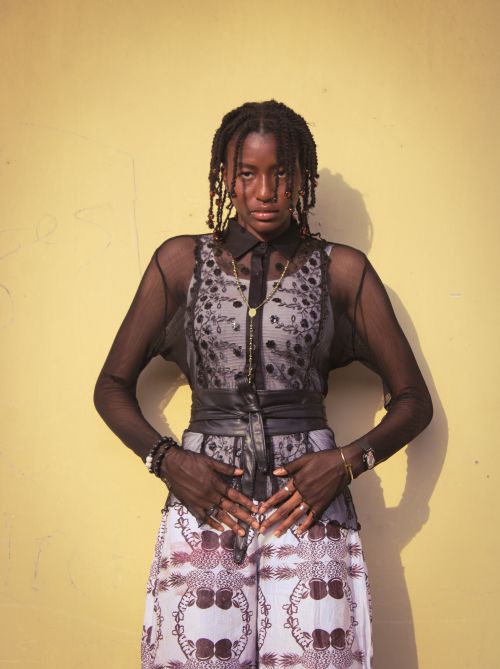 Free Fashion portrait of a woman in stylish attire against a yellow wall. Stock Photo