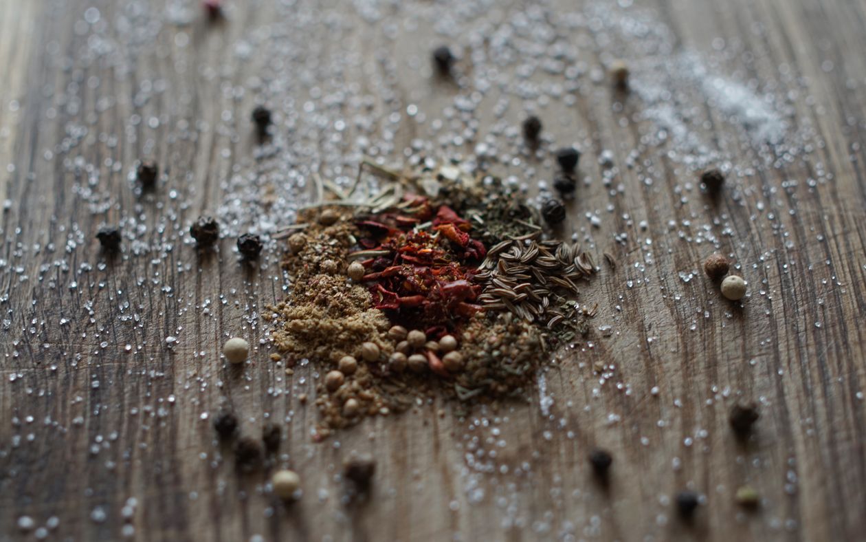 Mixed spices for jerk chicken seasoning on a rustic wooden surface