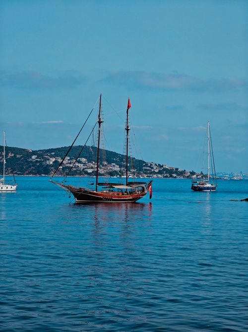 Free Peaceful scene of traditional boats anchored in a tranquil harbor with distant hills. Stock Photo