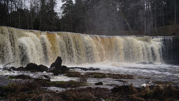 A powerful waterfall cascading through a forested landscape in winter.