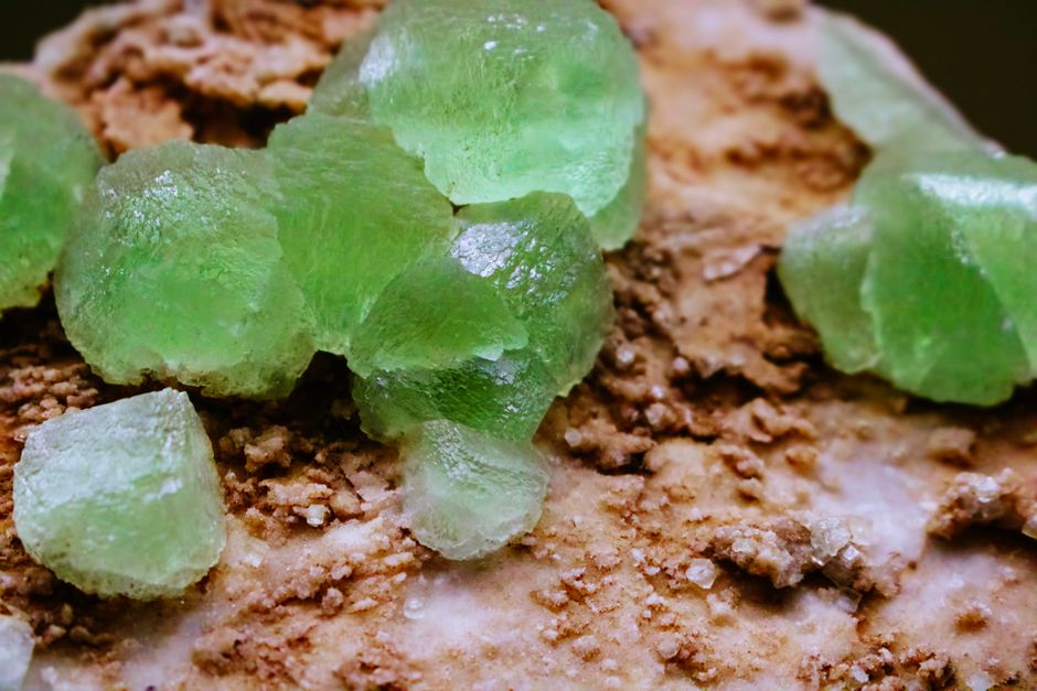 Close-up of bright green crystals on a textured mineral surface, showcasing natural beauty.
