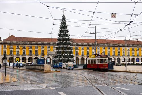 Free Tram in Lisbon's historic square with a festive Christmas tree and colonial architecture. Stock Photo