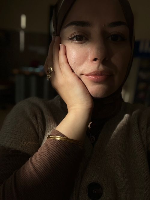 Free A thoughtful woman in soft indoor lighting, wearing a hijab and reflecting mood. Stock Photo