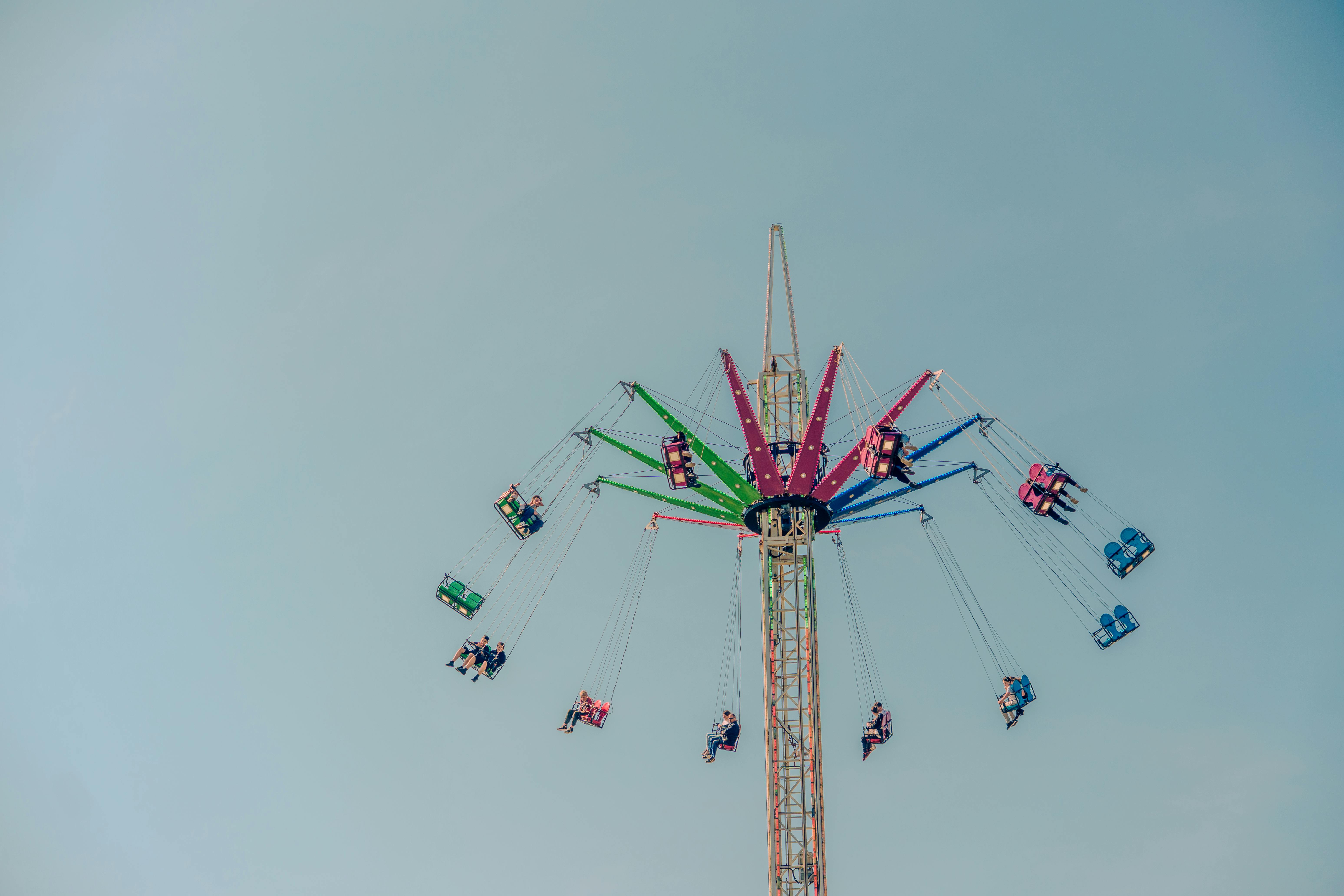 無料 屋外フェアで晴れた日を楽しむ人々が、カラフルなブランコに乗っています。 写真素材