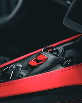 Close-up view of a luxury sports car's red-accented carbon fiber interior with sleek design elements.