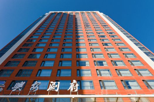Dramatic view of a modern high-rise building against a clear blue sky in Hohhot, Inner Mongolia.