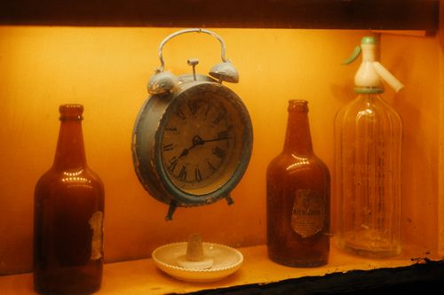 Free A warm, vintage display featuring a rustic alarm clock surrounded by antique bottles. Stock Photo