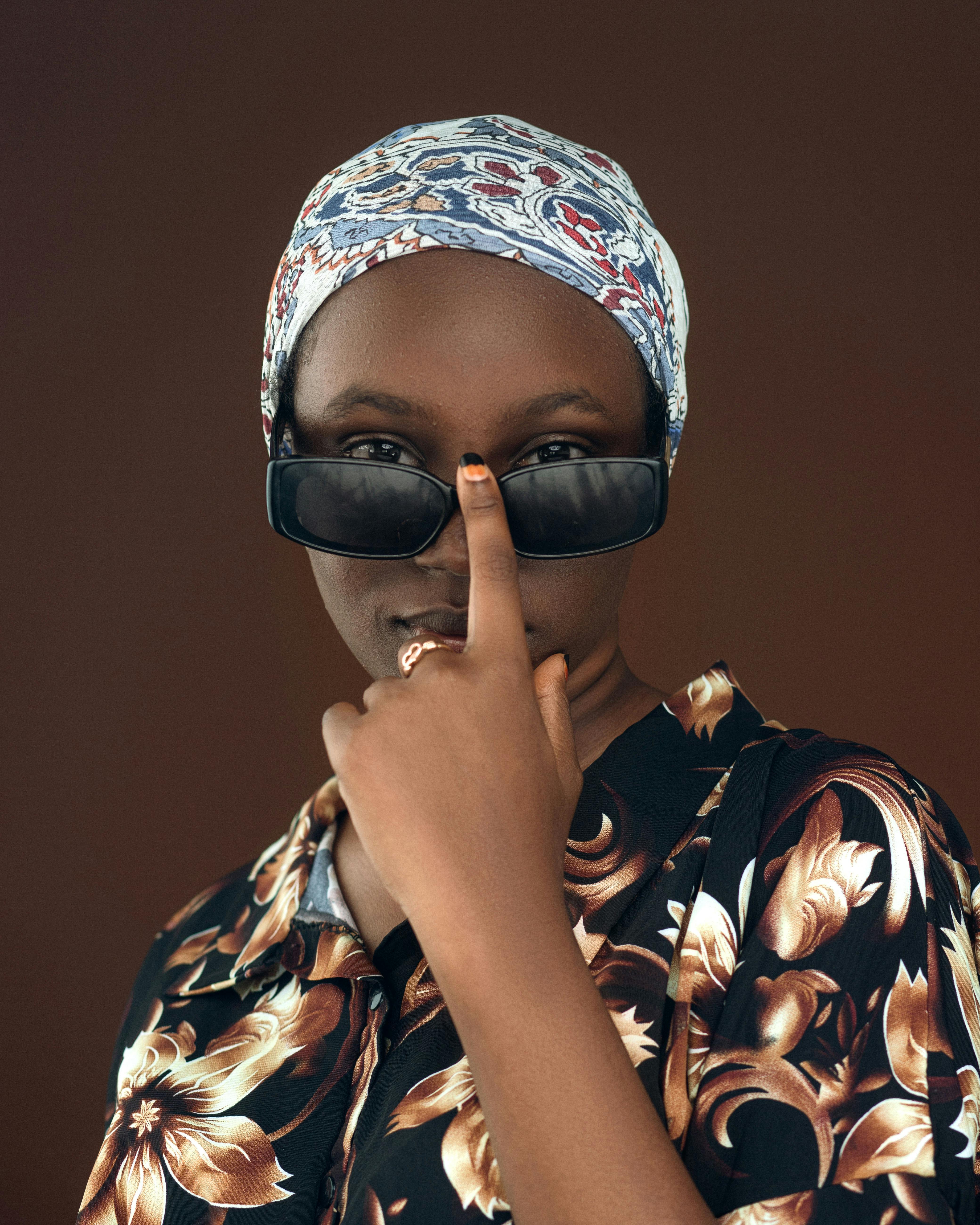 Gratis Mujer africana segura de sí misma, con gafas de sol y un atuendo floral, haciendo una pose. Foto de stock